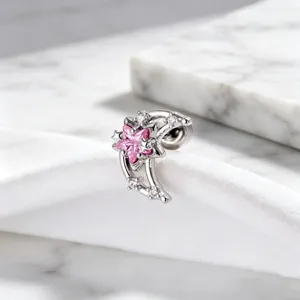 Close-up of pink star and moon earring with zircon accents on marble