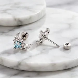 Detail view of sparkling moon and star stud earrings with light blue zircon stones