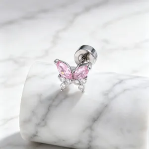 Close-up of pink butterfly surgical steel stud earring on white marble base