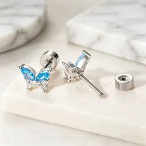 Macro detail of medical titanium butterfly stud earrings with sparkling blue zirconia stones