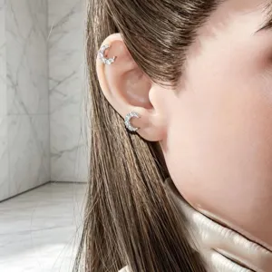 Sparkly silver crescent moon ear studs shown on Asian female model in minimalist setting