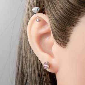 Vue détaillée de boucles d'oreilles coquillage en acier titane avec pierres roses