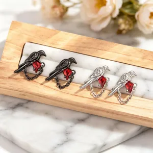 Detailed macro shot of bird-shaped earrings featuring red rhombic zircon and chains