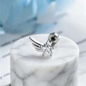 Macro detail of minimalist silver star zircon wing earring on white marble display