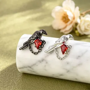 Detail view of bird-shaped earrings with red kite zircon stones and chain accents.