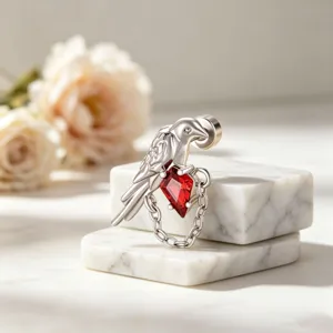 Elegant close-up of a silver bird ear cuff with red rhombus zircon and chain detail