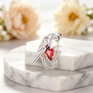 Close-up detail of a silver bird earring featuring a sparkling red kite-shaped zircon stone.