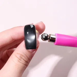 Detail of pink cat eye nail magnet tool creating magnetic effects on black false nail tip