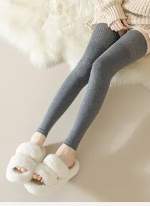 Close-up detail of grey knitted over-the-knee leg warmers, cozy winter style, soft fabric.