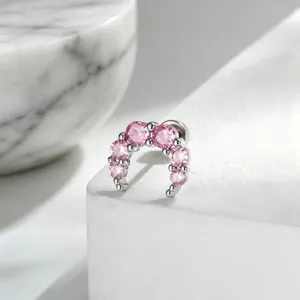 Close-up view of a crescent moon ear bone nail featuring sparkling pink gemstones.