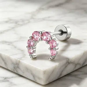 Detailed view of a silver crescent moon ear stud featuring pink pavé set gemstones.