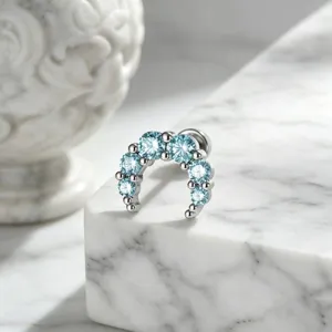 Close-up detail of moon-shaped ear piercing stud with sparkling light blue crystals