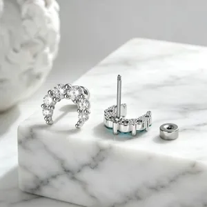 Close-up of sparkling crescent moon ear studs with cubic zirconia and screw back detail.