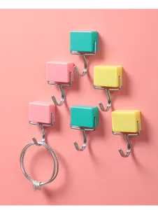 Bunte japanische Magnet haken an einer rosa Wand halten einen kleinen Metall ring