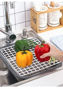 Rejilla de drenaje blanca para fregadero con pimientos frescos para un lavado eficaz.