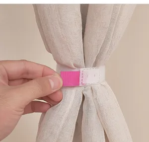 Gros plan d'une sangle Velcro rose et blanche attachant un rideau beige transparent.