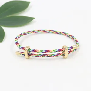 Vista detallada de pulsera trenzada colorida con hebilla deslizante dorada ajustable.