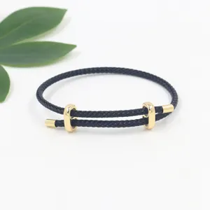Vista detallada de una pulsera trenzada negra ajustable con cierre dorado en forma de ocho.