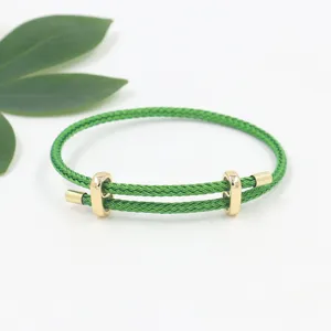 Vista detallada de la pulsera de cable trenzado verde con hebillas doradas ajustables.