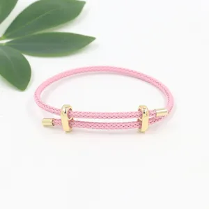 Vista detallada de la pulsera de cuerda trenzada rosa con hebillas doradas ajustables.