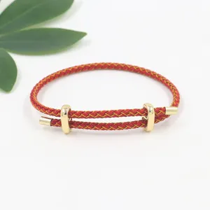 Primer plano de una pulsera de cuerda trenzada roja con hebilla dorada ajustable.