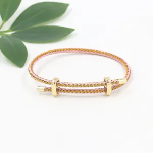 Detalle de pulsera de cable trenzado rosa y dorado con cierres deslizantes.