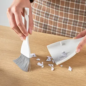Ergonomische mini desktop reinigingsset met witte bezem en stoffer op houten tafel