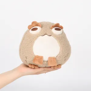 Primer plano de un suave peluche de sapo marrón redondo sostenido en la mano