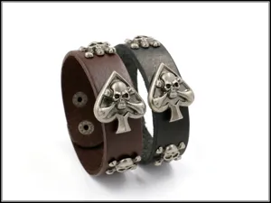 Primer plano de pulseras de cuero punk con remaches de calavera y motivo de pica central