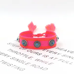 Detailansicht eines handgewebten Ethno-Armbands mit Türkis-Nieten und rosa Quasten