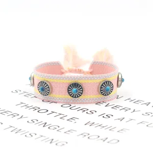 Nahaufnahme eines handgewebten Ethno-Armbandes mit Metallnieten und blauen Türkissteinen.