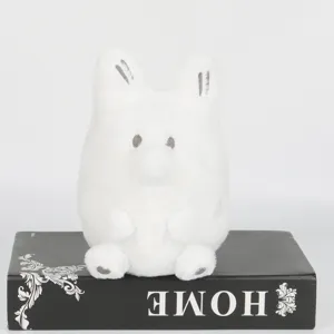 Vue macro détaillée de la peluche blanche Anxiety Fox posée sur un livre de décoration