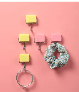 Detailansicht bunter Magnethaken, die ein Haargummi und einen Ring auf Rosa halten.