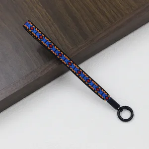 Etnische geweven polsband met kleurrijk geometrisch patroon en metalen ringhouder.