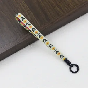 Ethnic floral woven phone lanyard with black metal ring, short hand strap accessory.