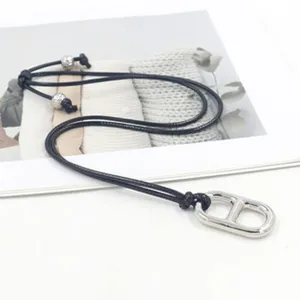 Detail view of a stainless steel oval link pendant on a black adjustable cord necklace