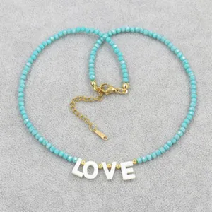 Detail of turquoise beaded necklace with white 'LOVE' letter beads and gold clasp