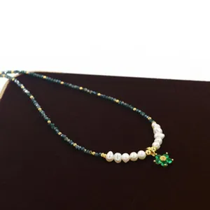 Close-up of a stainless steel aromatherapy necklace with pearls and green flower pendant