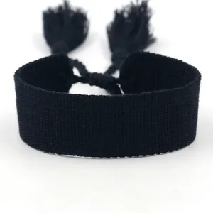 Detailed view of the woven texture on a solid black fabric bracelet with tassels