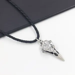 Close-up of Viking raven skull pendant with engraved Vegvisir symbol on leather cord.