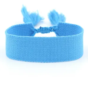 Close-up of sky blue woven fabric ribbon bracelet with decorative tassels