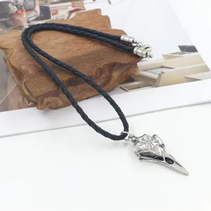 Close-up of Viking crow skull pendant with Norse engravings on braided leather cord.