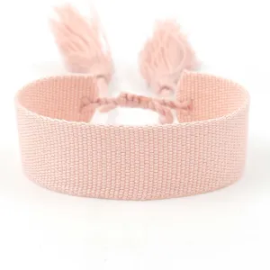 Close-up detail of a soft pink woven textile bracelet with tassels for DIY embroidery