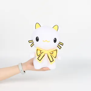 Peluche chat blanc avec nœud papillon jaune tenue à la main pour montrer la taille