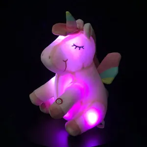 Detalle de un peluche de unicornio LED rosa brillante con coloridas alas de arcoíris