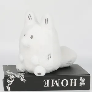 Gros plan d'une peluche Anxiety Fox blanche posée sur un livre noir décoratif