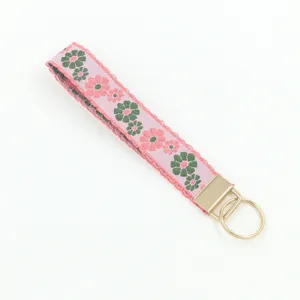 Close-up detail of ethnic floral embroidery on pink fabric wristlet keychain