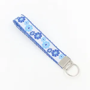 Detailed view of the blue floral embroidery and silver hardware of the wristlet