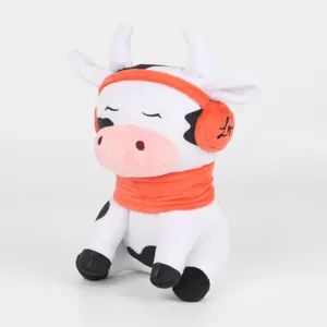 Primer plano detallado del peluche vaca Chilledcow con bufanda y orejeras naranjas