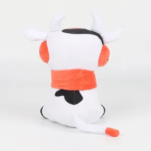 Vista trasera detallada de una linda vaca de peluche con bufanda y orejeras naranjas